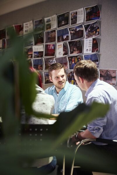 Ian Stickland in a meeting with two colleagues, images pinned to a grey wall behind them